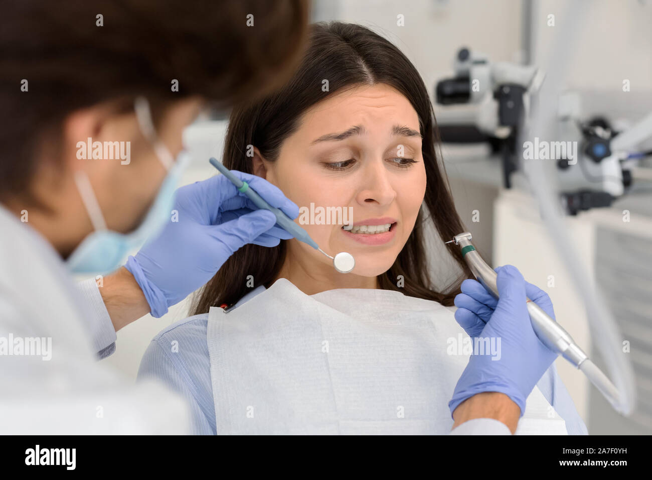 Scared woman at dental office, looking panickly at dental tools Stock Photo