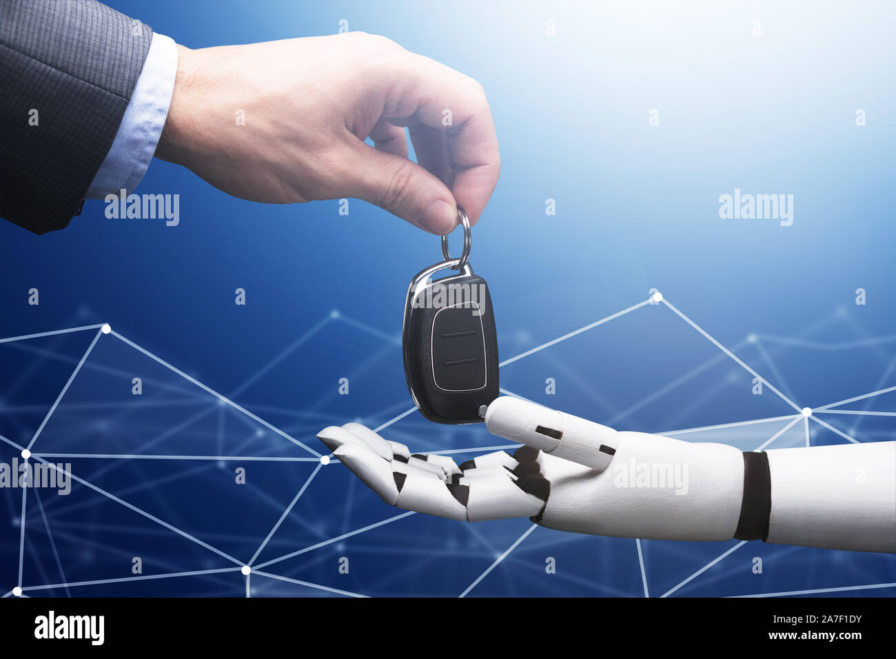 Close-up Of A Businessperson's Hand Giving Car Key To Robot On Blue Technology Background Stock Photo