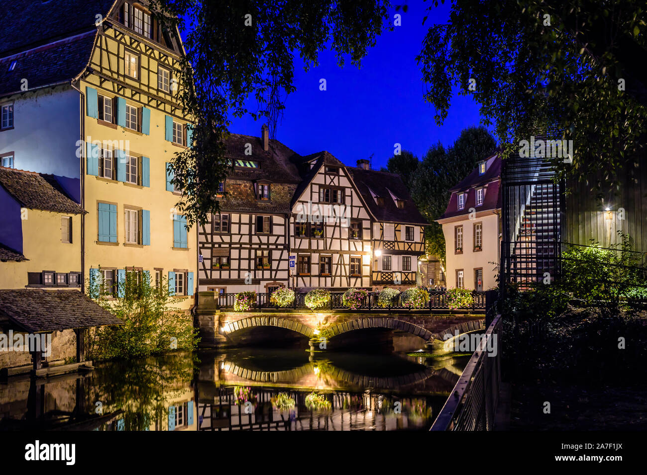 Night view of the bridge spanning the canal in the Petite France quarter in Strasbourg, France, lined by half-timbered houses reflecting in the water. Stock Photo