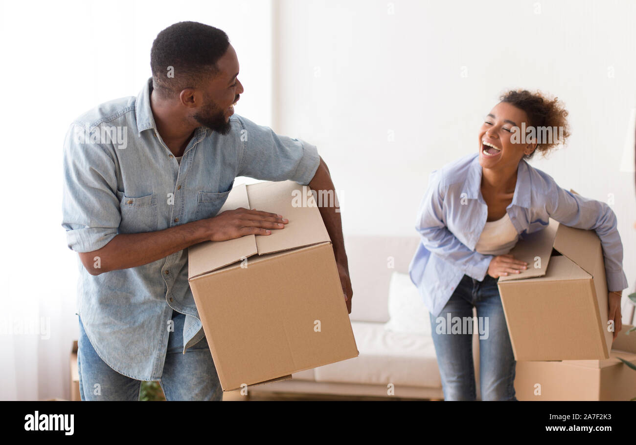 African American Couple Carrying Moving Boxes Entering New Apartment Stock Photo