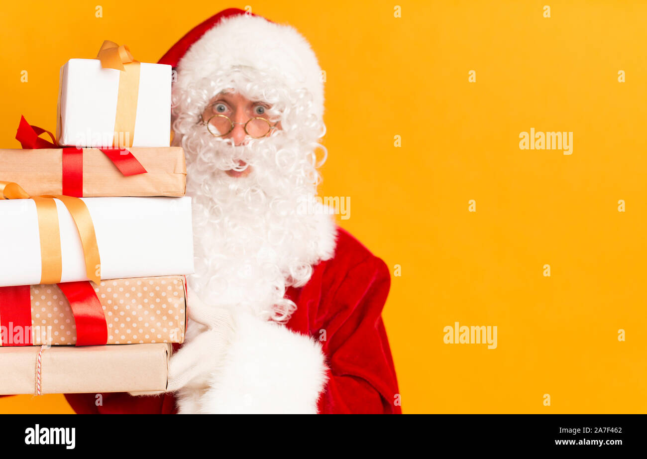 Santa holding gift boxes on bright orange background Stock Photo - Alamy