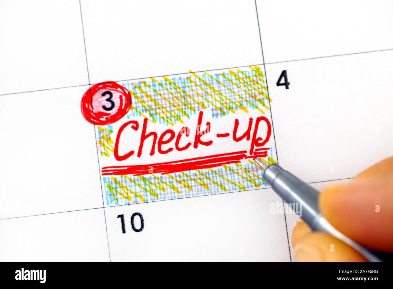 Woman fingers with pen writing reminder Check-up in calendar. Close-up. Stock Photo