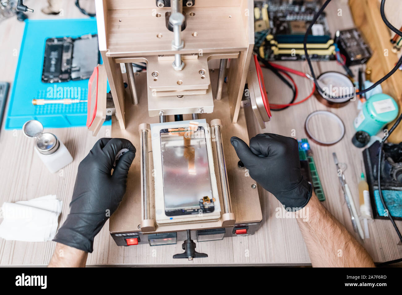 Gloved hands of professional repairman using equipment for gadget repair Stock Photo