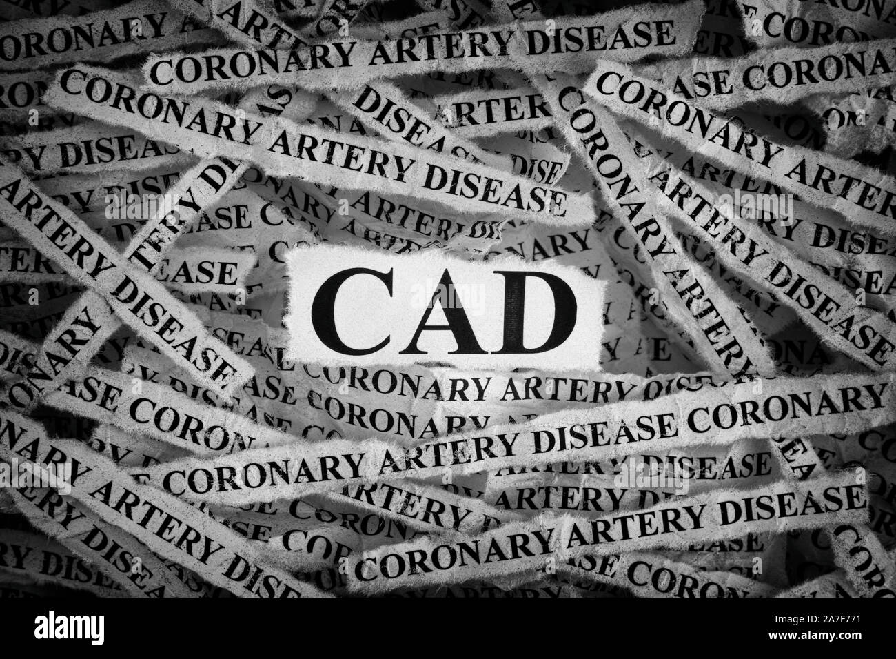 CAD. Torn pieces of paper with the word CAD (Coronary Artery Disease). Concept image. Black and White. Close up. Stock Photo