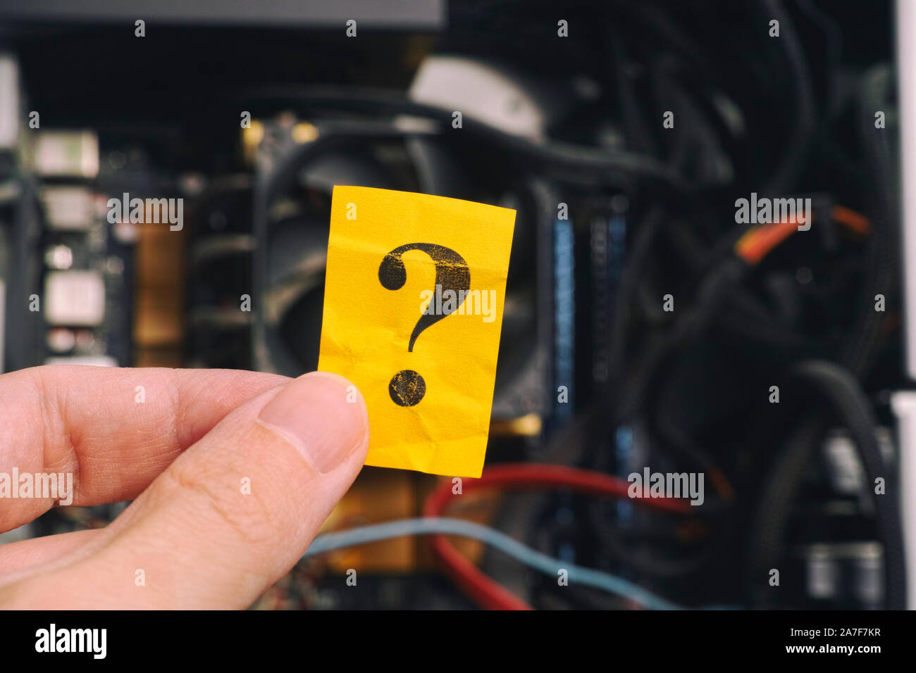 Hand holding question mark against open pc case. Close up. Stock Photo