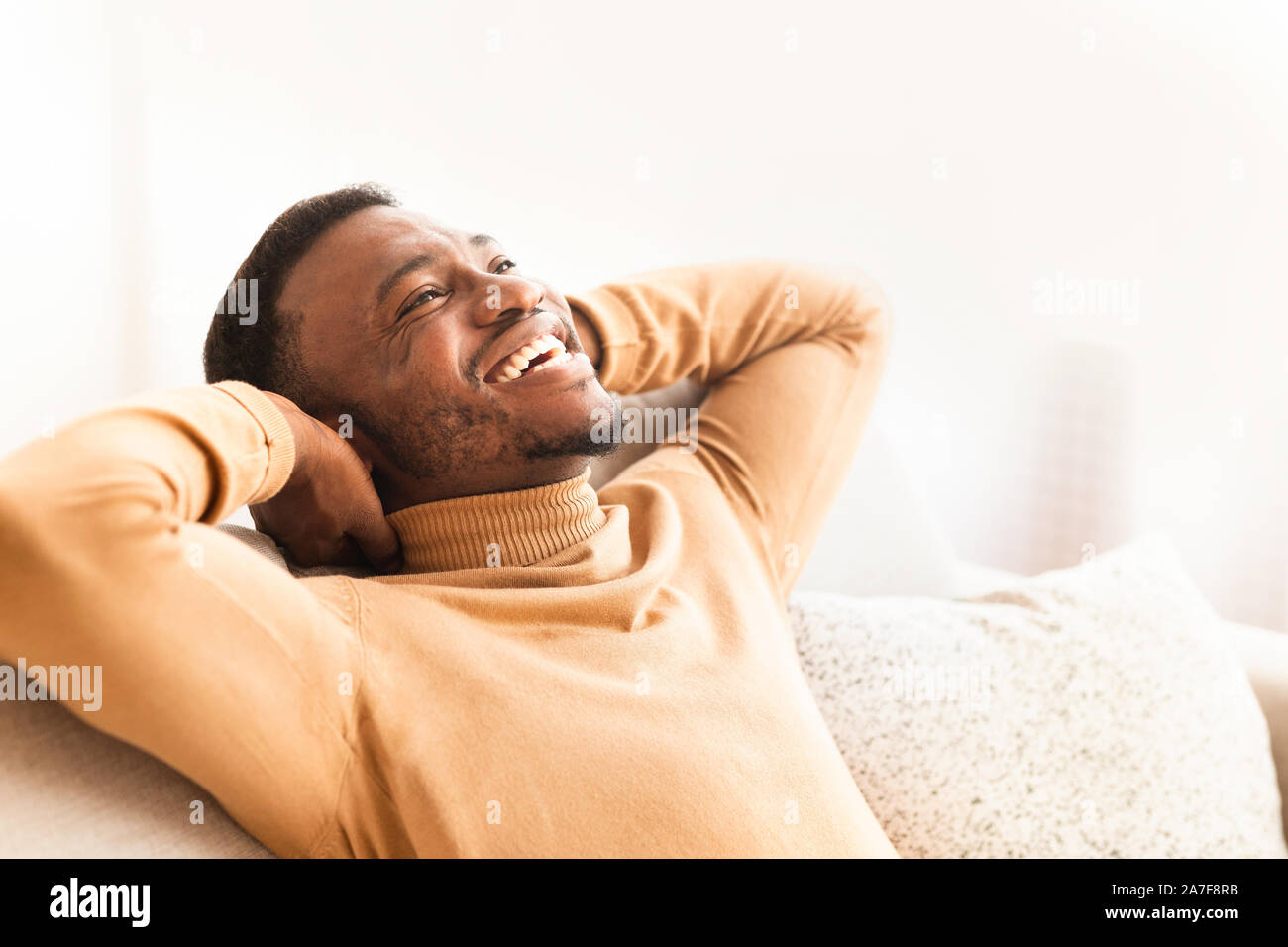 Happy Black Guy Relaxing Sitting On Couch At Home Stock Photo