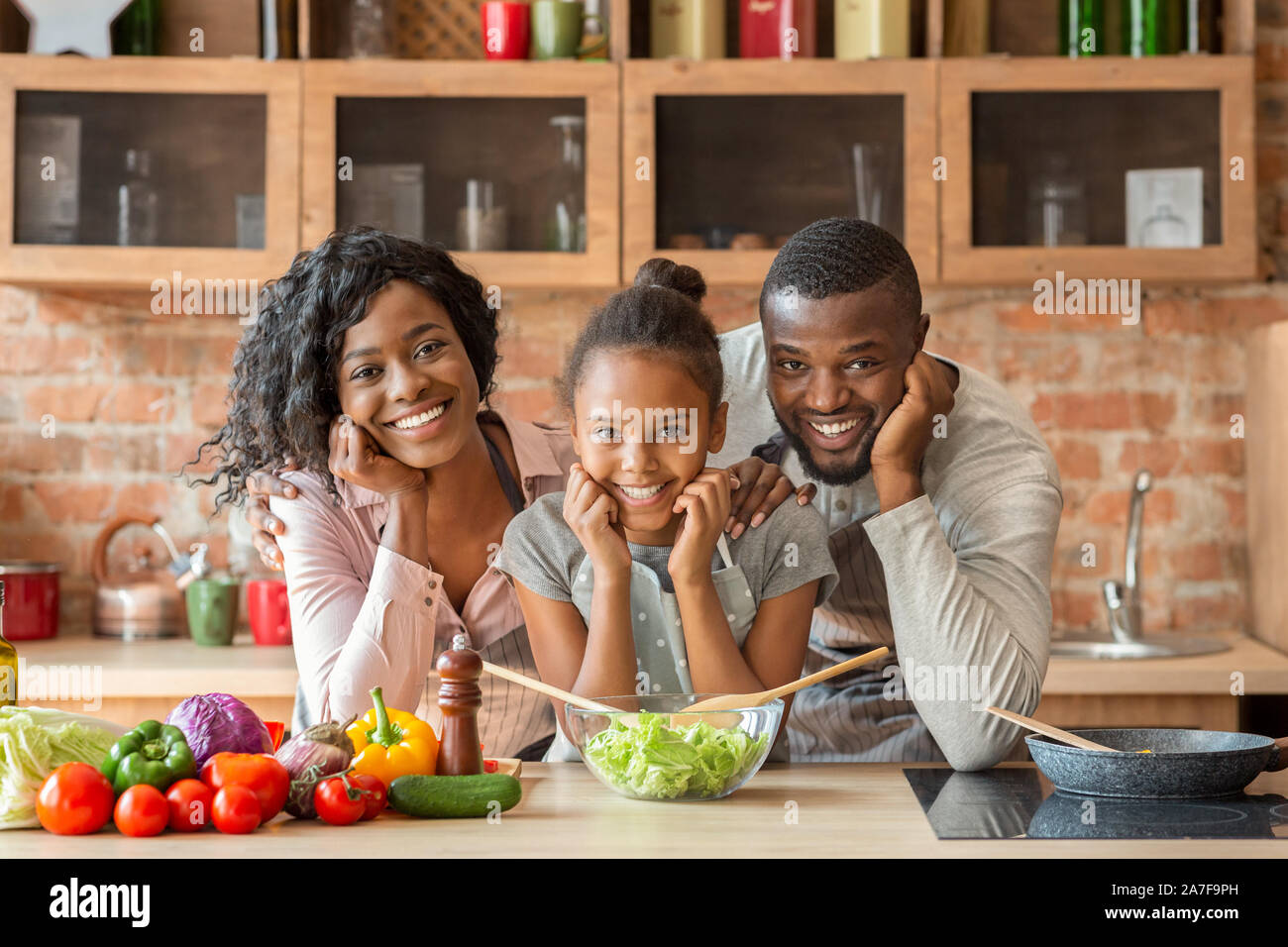 Adorable black family cooking healthy dinner together at kitchen Stock