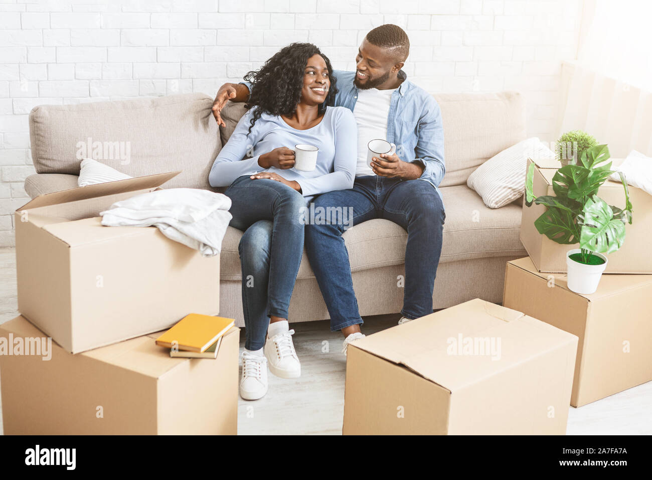 Happy couple taking break, unpacking on moving day Stock Photo