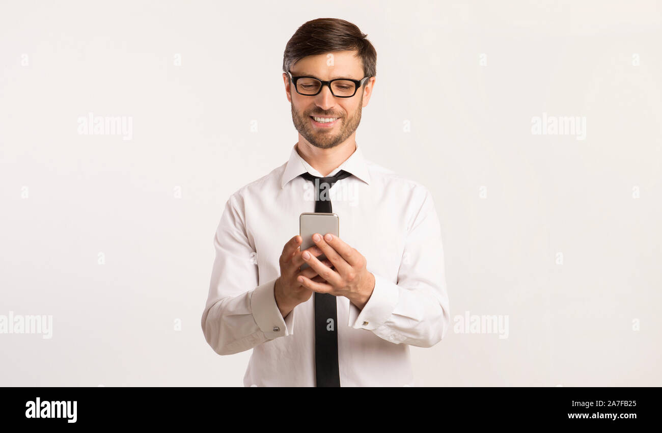 Smiling Man Texting On Cellphone Over White Background Stock Photo