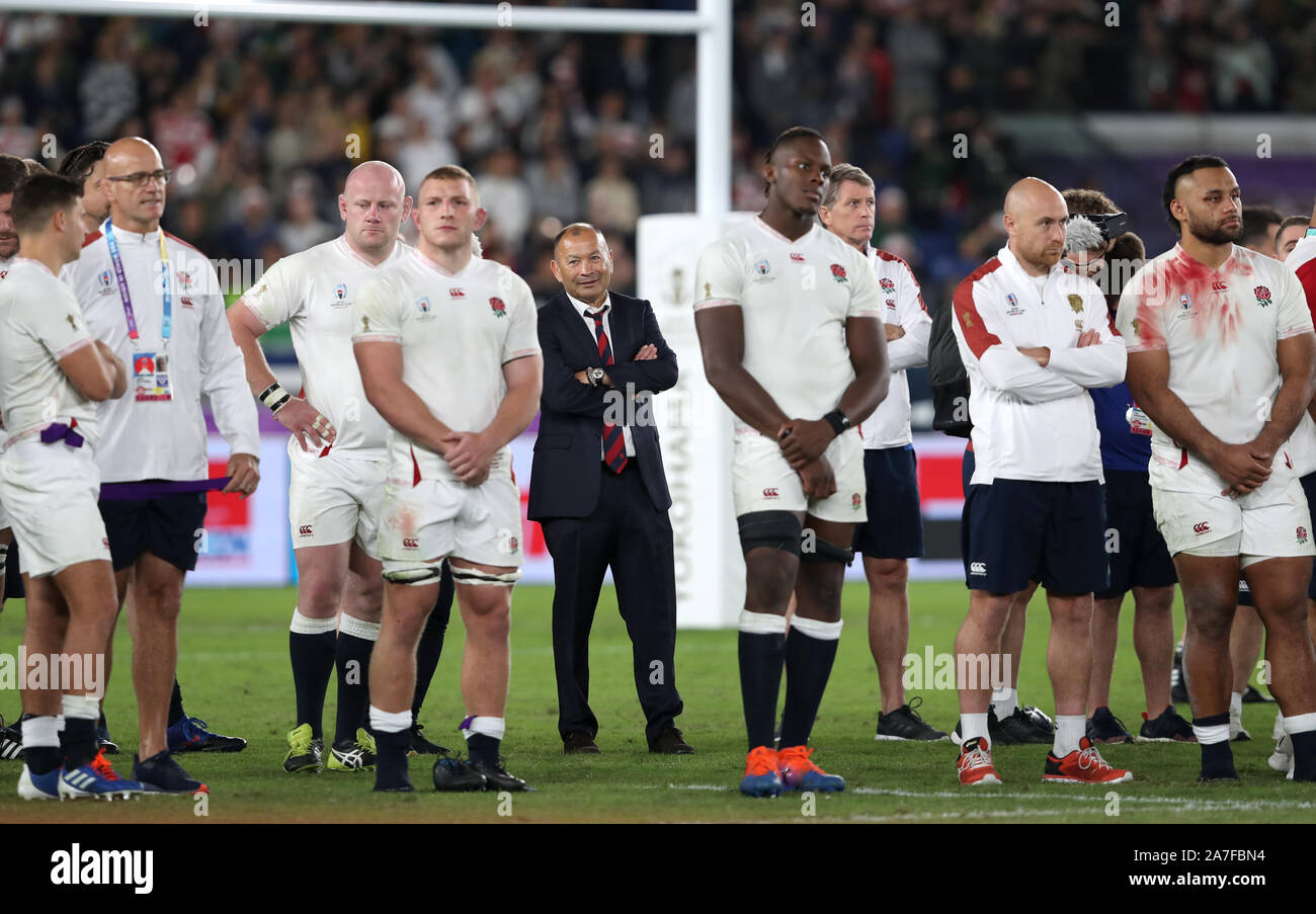 England head coach Eddie Jones (centre) stands with his players as South Africa lift the Webb Ellis Cup after the 2019 Rugby World Cup final match at Yokohama Stadium. Stock Photo
