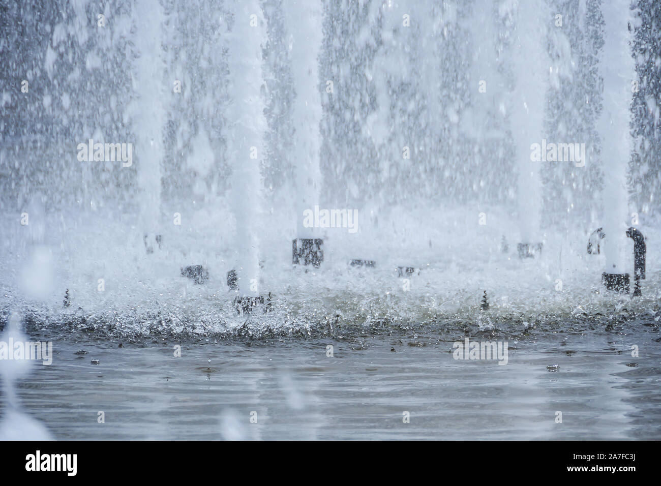 Water fountain jets shooting upwards and splashing in pool of water