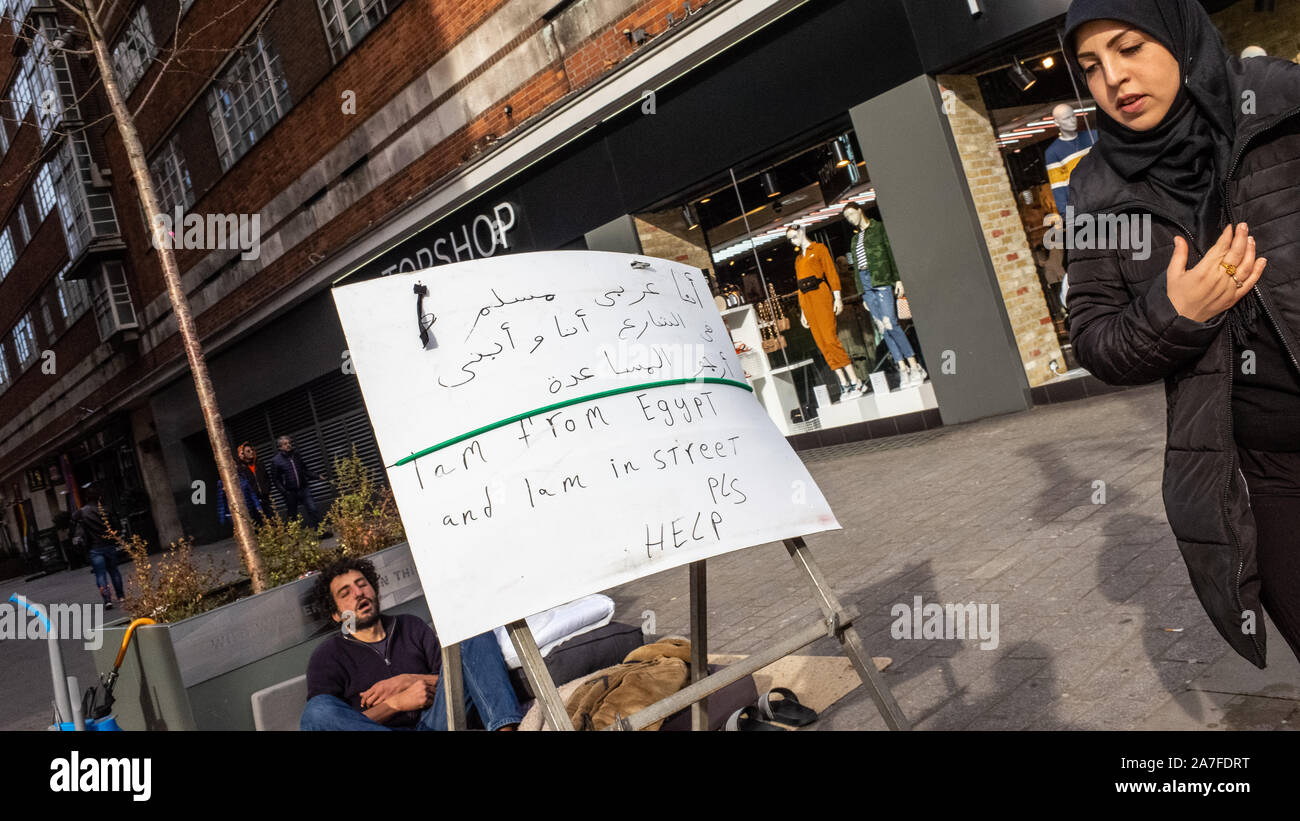 A homeless Egyptian man asks for help in Arabic and English on London's Oxford Street, UK Stock Photo