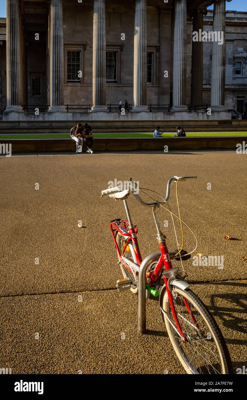Summer scene at Londons British Museum. Warm sun, bike and people in the background Stock Photo