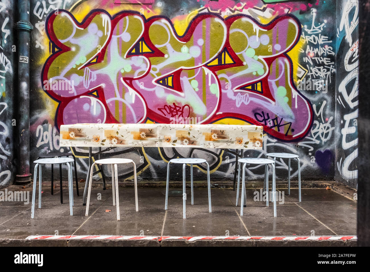 Empty table and chairs in a small graffitied alcove just off Portobello Road Market. Stock Photo