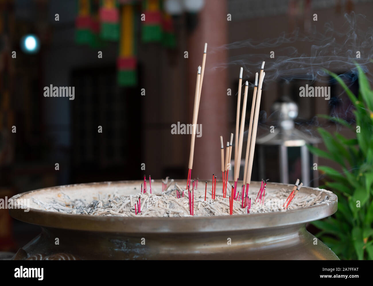 Multiple Joss incense sticks burning with smoke and ash after prayers