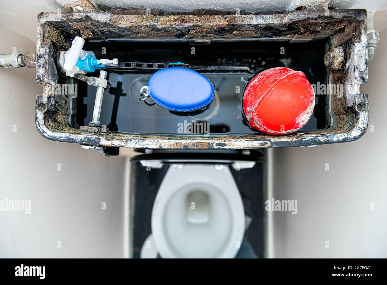 Flat top closeup looking down on broken toilet with soiled dirty old material inside with pump and water in narrow bathroom in United Kingdom Stock Photo