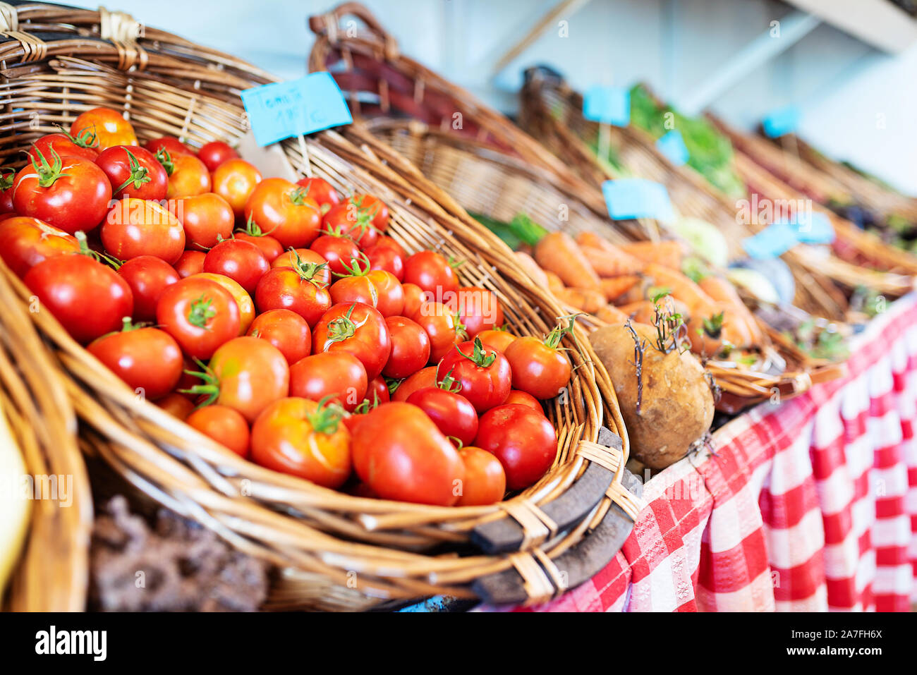 close-up of fresh ripe organic tomatoes in wicker basket at market stall Stock Photo