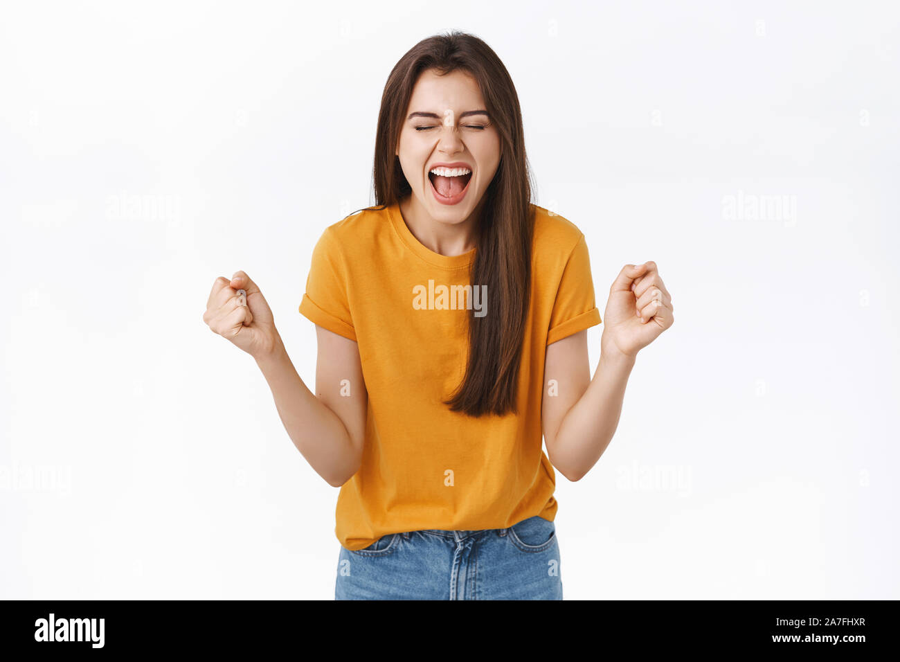 Relieved, happy woman rejoicing in yellow t-shirt, clench fists and smiling joyfully, achieve success, got lucky winning prize, become champion, close Stock Photo