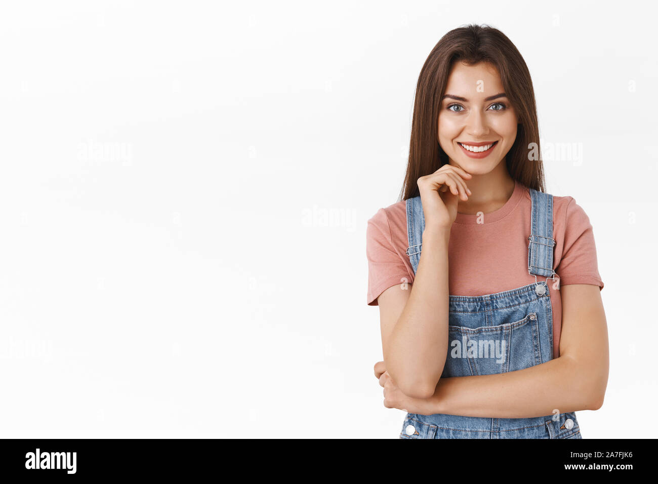 Confident, alluring stylish young caucasian woman in dungarees over t-shirt, touching face and smiling pleased, hear interesting concept, made final Stock Photo