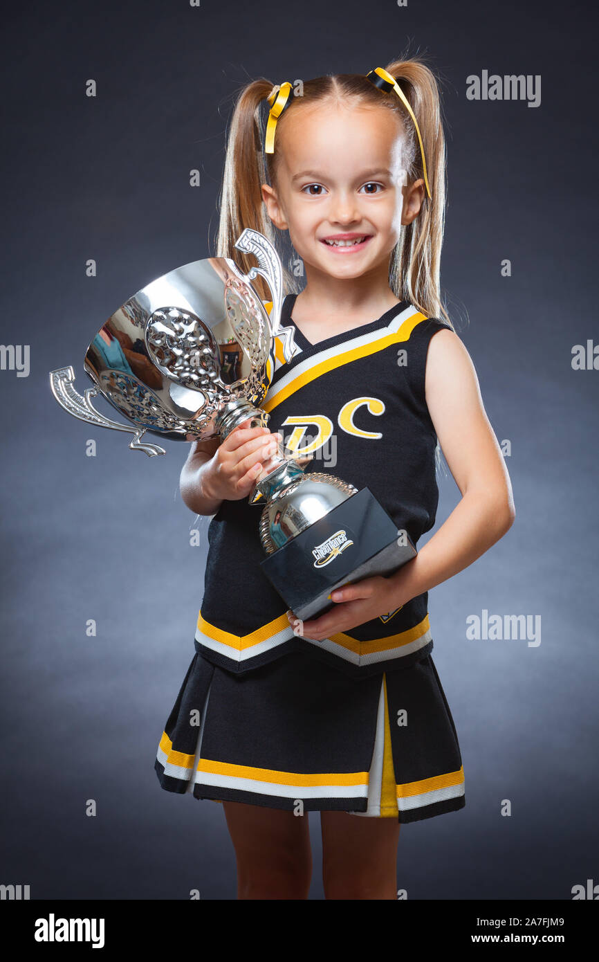 A young Caucasian girl dressed in a Cheer Dance outfit and holding a trophy. England, UK. Stock Photo