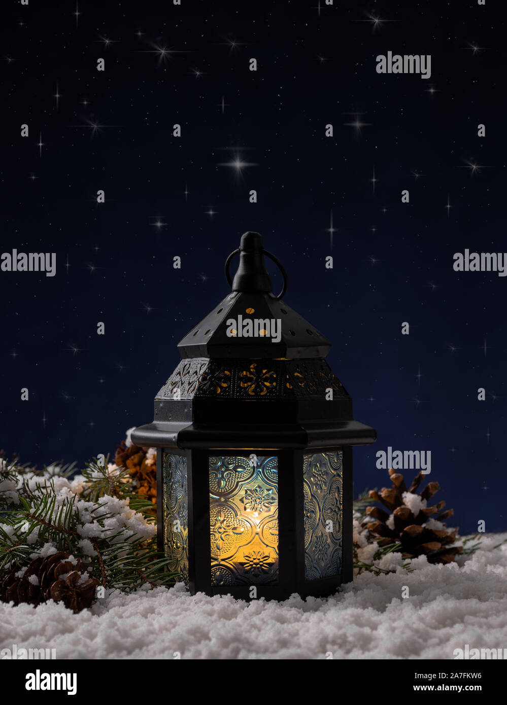 Glowing Christmas lantern on snow against a night sky background with shining stars Stock Photo