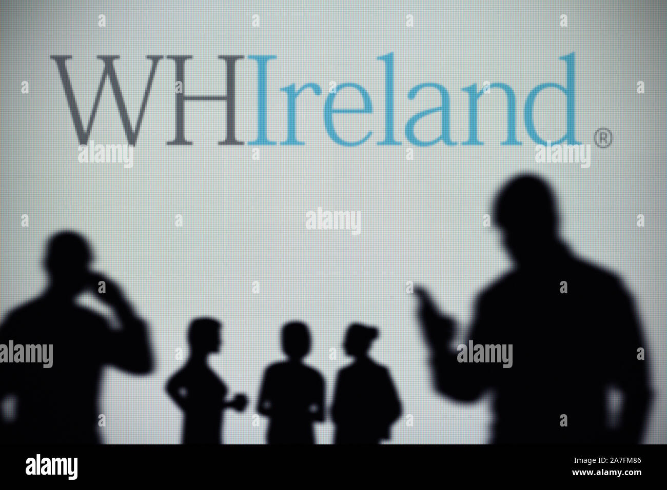 The WHIreland logo is seen on an LED screen in the background while a silhouetted person uses a smartphone (Editorial use only) Stock Photo