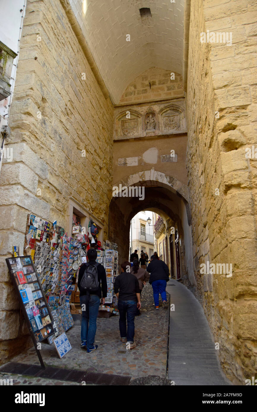 People pass under the old gate of the Arch of Almedina in Coimbra Portugal Stock Photo