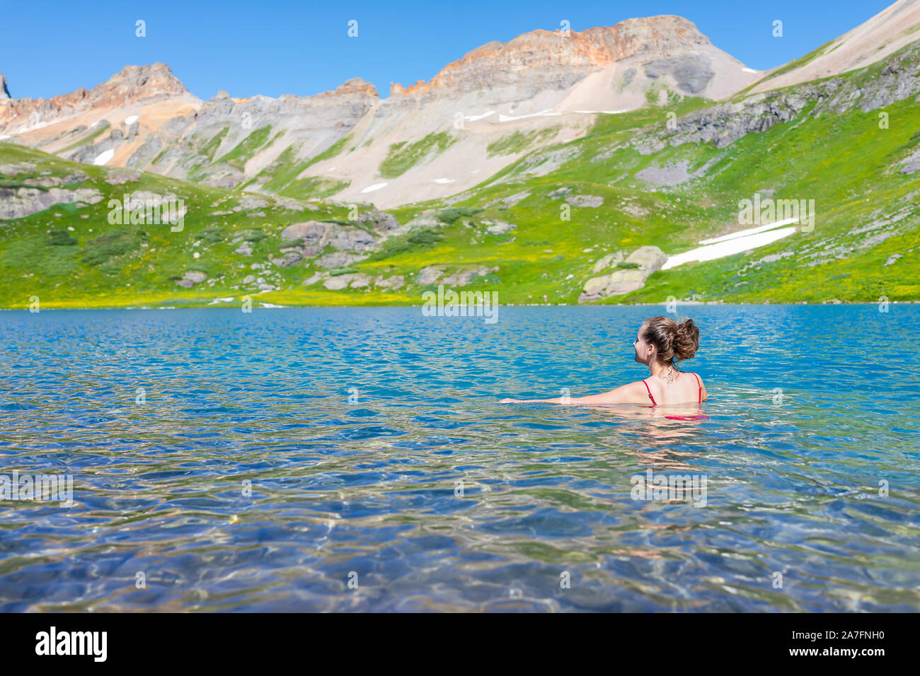 Young woman girl swimming cold colorful water of Ice Lake on famous trail in Silverton, Colorado in San Juan Mountains in summer Stock Photo
