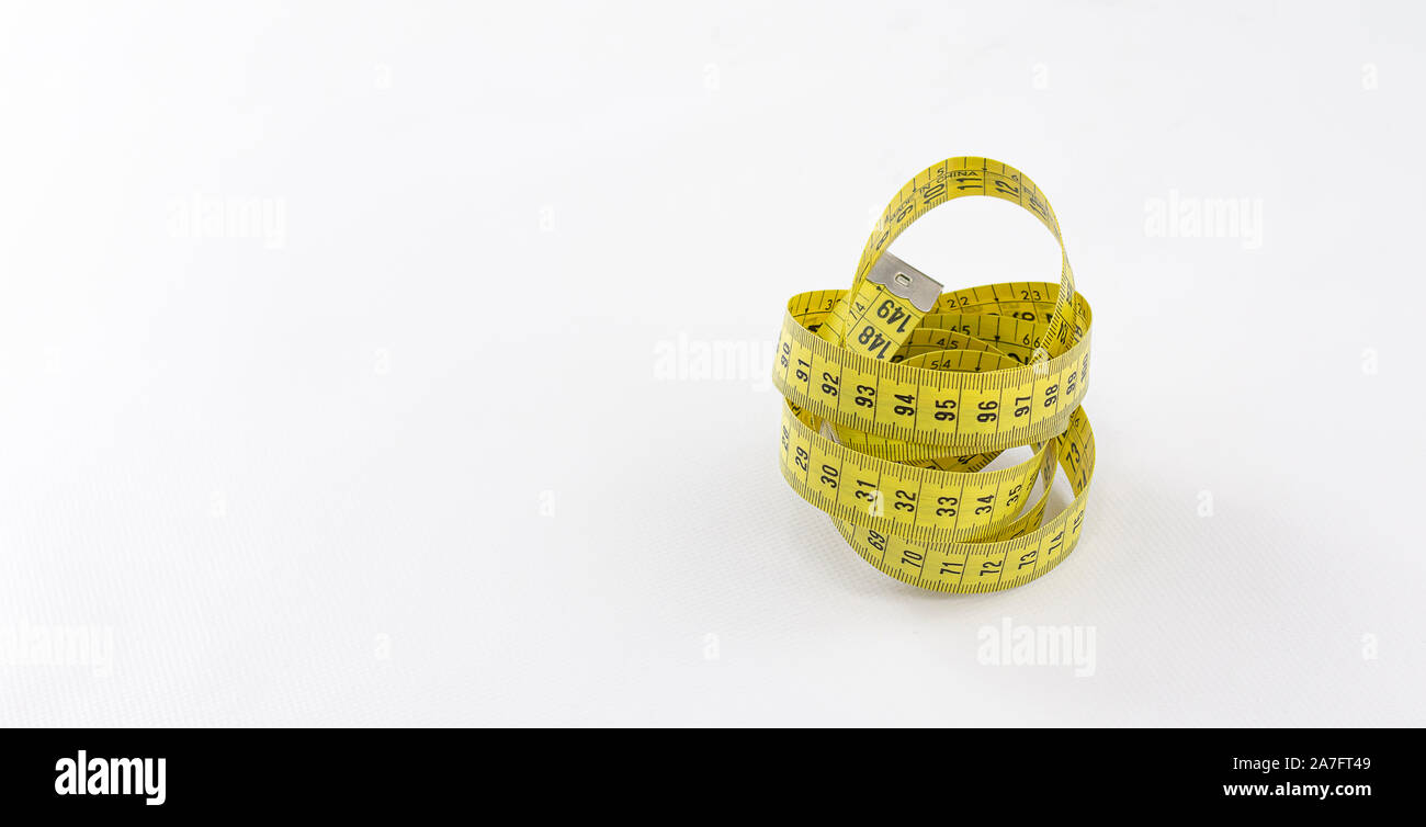 Yellow tape measure with black numbering rolled on itself and metallic terminal over white background Stock Photo