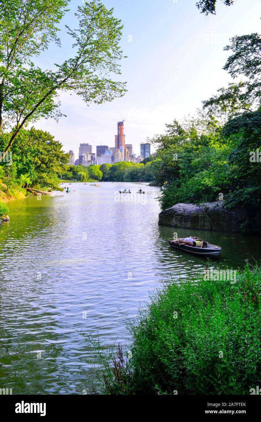 Boats on The Lake at Central Park, Manhattan, NYC, New York, USA.  Looking southwest  with Sheep Meadow, Midtown and Times Square in background. Stock Photo