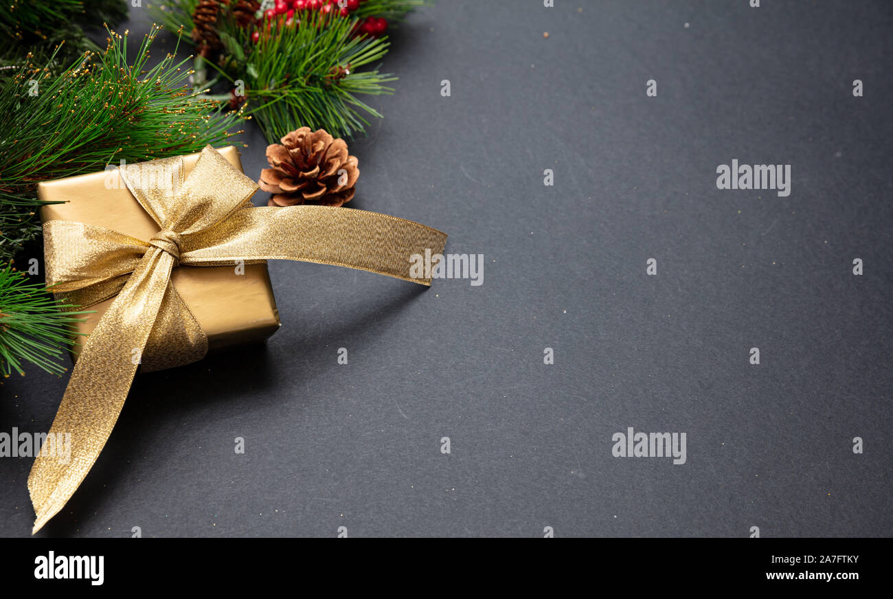 Christmas present. Xmas gift box shiny gold color against dark gray background, high angle, copy space Stock Photo