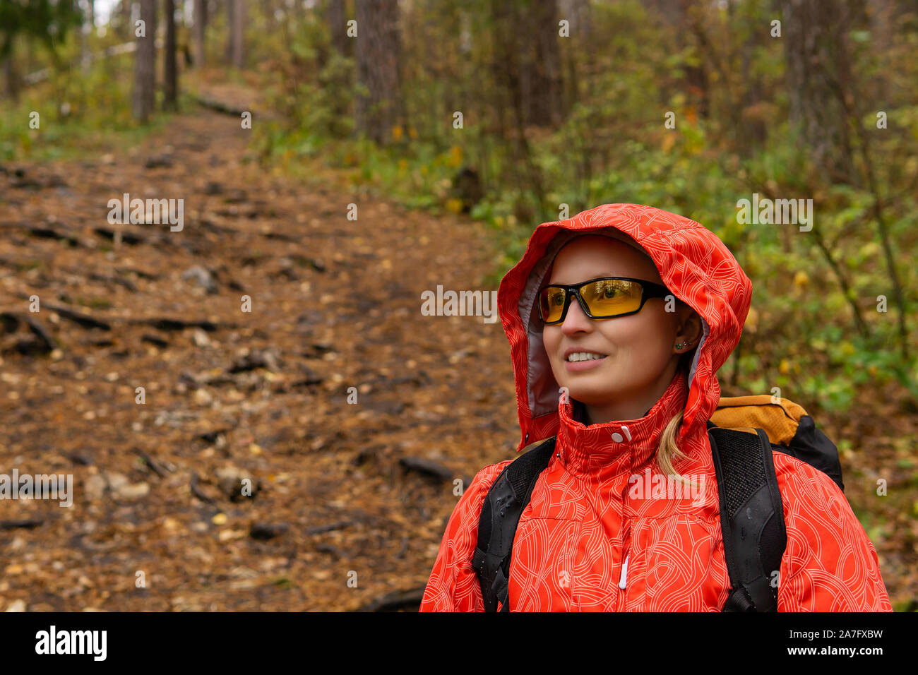 young blonde female hiker with backpack in autumn forest, half-length portrait Stock Photo