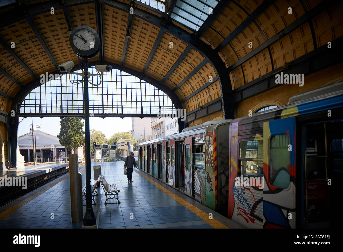 Piraeus port city Greece underground metro terminus of Athens Metro Line 1 a graffiti covers train departs under he ornate station shed roof Stock Photo
