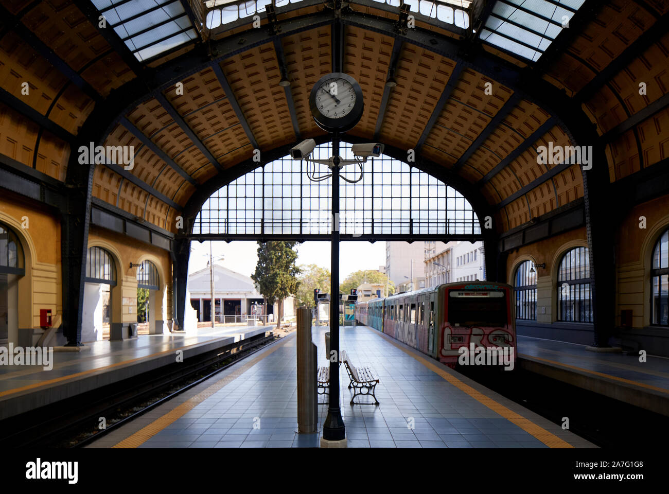 Piraeus port city Greece underground metro terminus of Athens Metro Line 1 a graffiti covers train departs under he ornate station shed roof Stock Photo