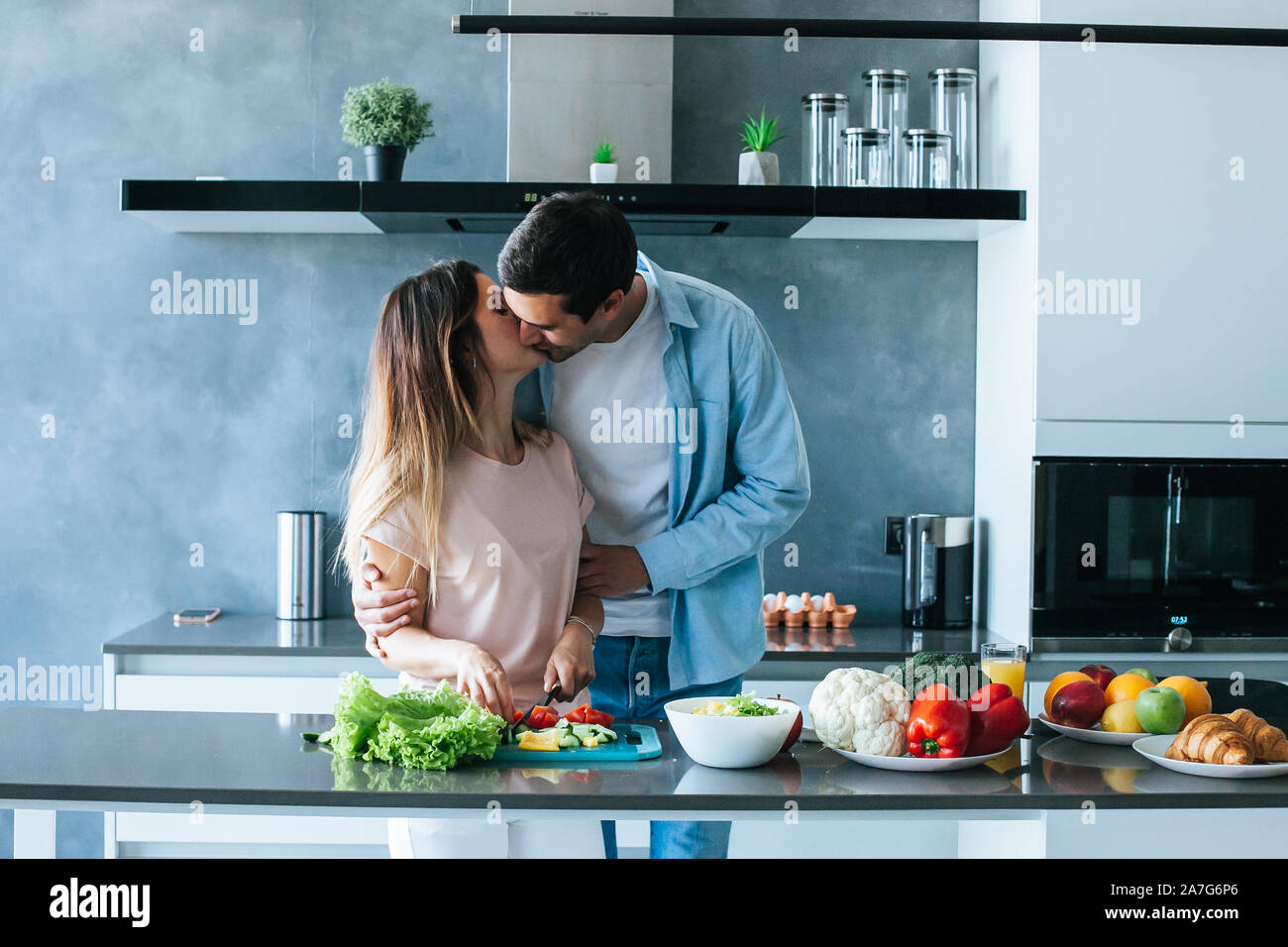 Happy young couple embracing during breakfast in kitchen Stock Photo