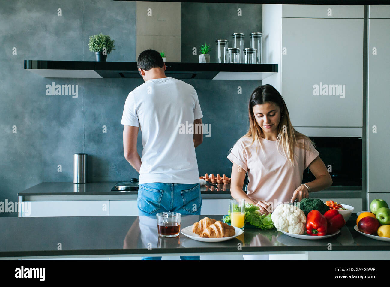 married young couple preparing breakfast in the morning in a bright kitchen Stock Photo