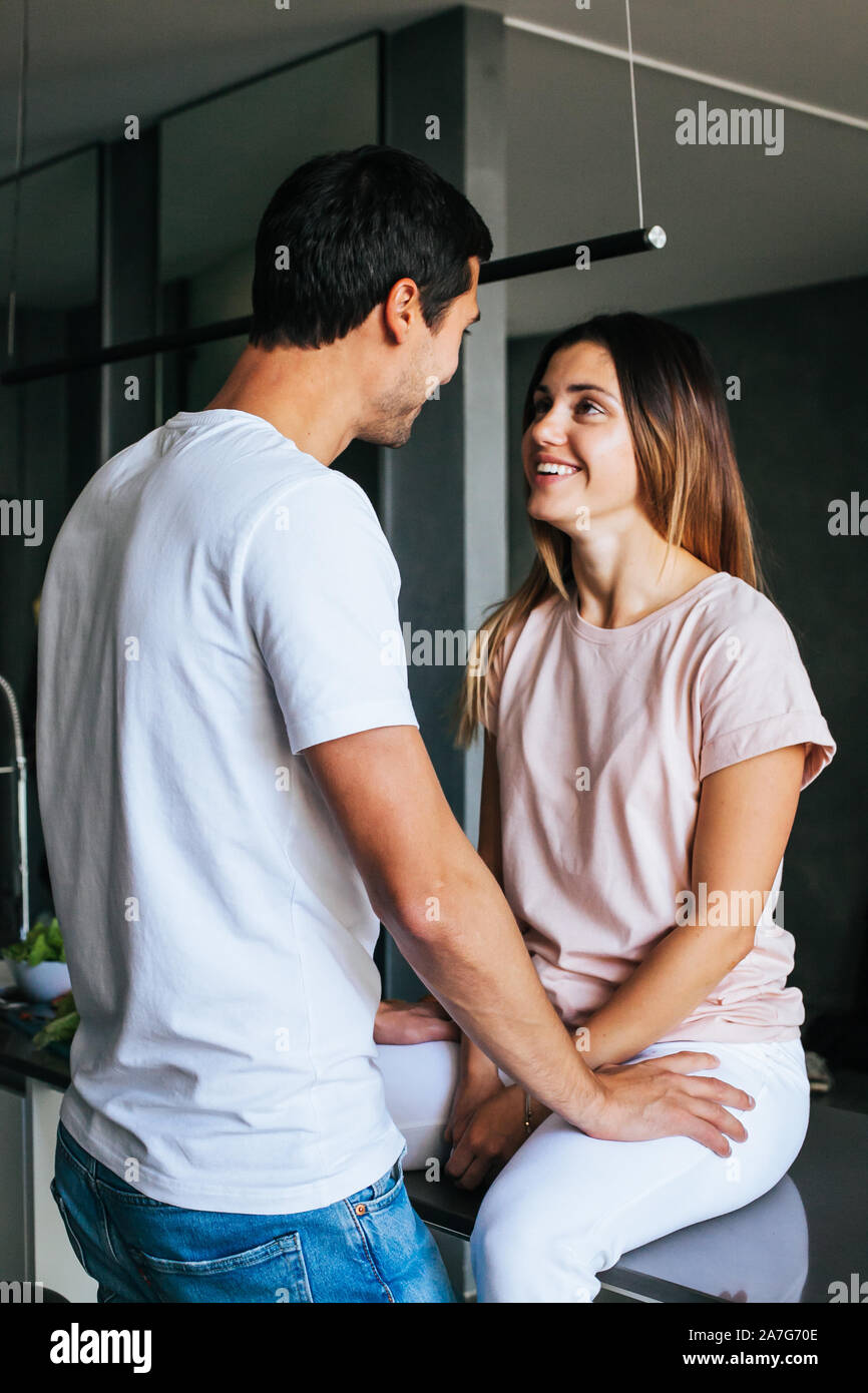 Happy couple in love communicates laughing in the morning in the kitchen Stock Photo