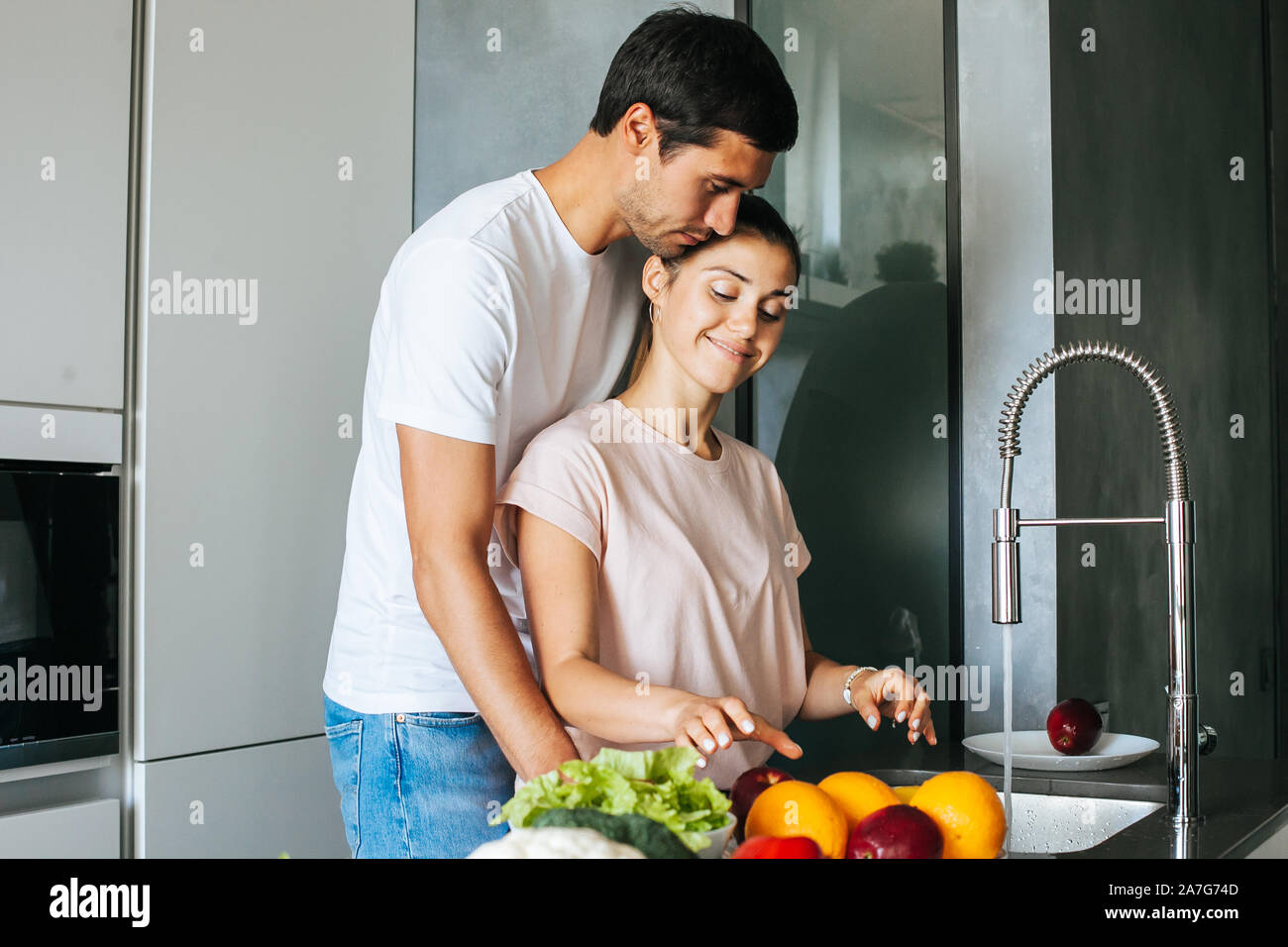 Happy young couple embracing during breakfast in kitchen Stock Photo