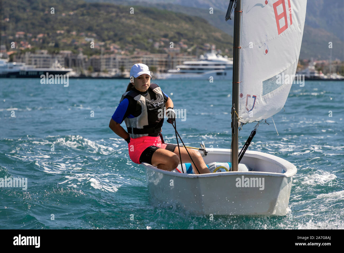 Montenegro, Sep 20, 2019: Teenage girl sailing in Optimist Class dinghy during the regatta in Kotor Bay Stock Photo