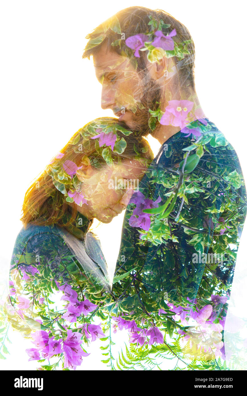 Double exposure portrait of man and woman happily embracing and dissolving into healthy tropical plants Stock Photo