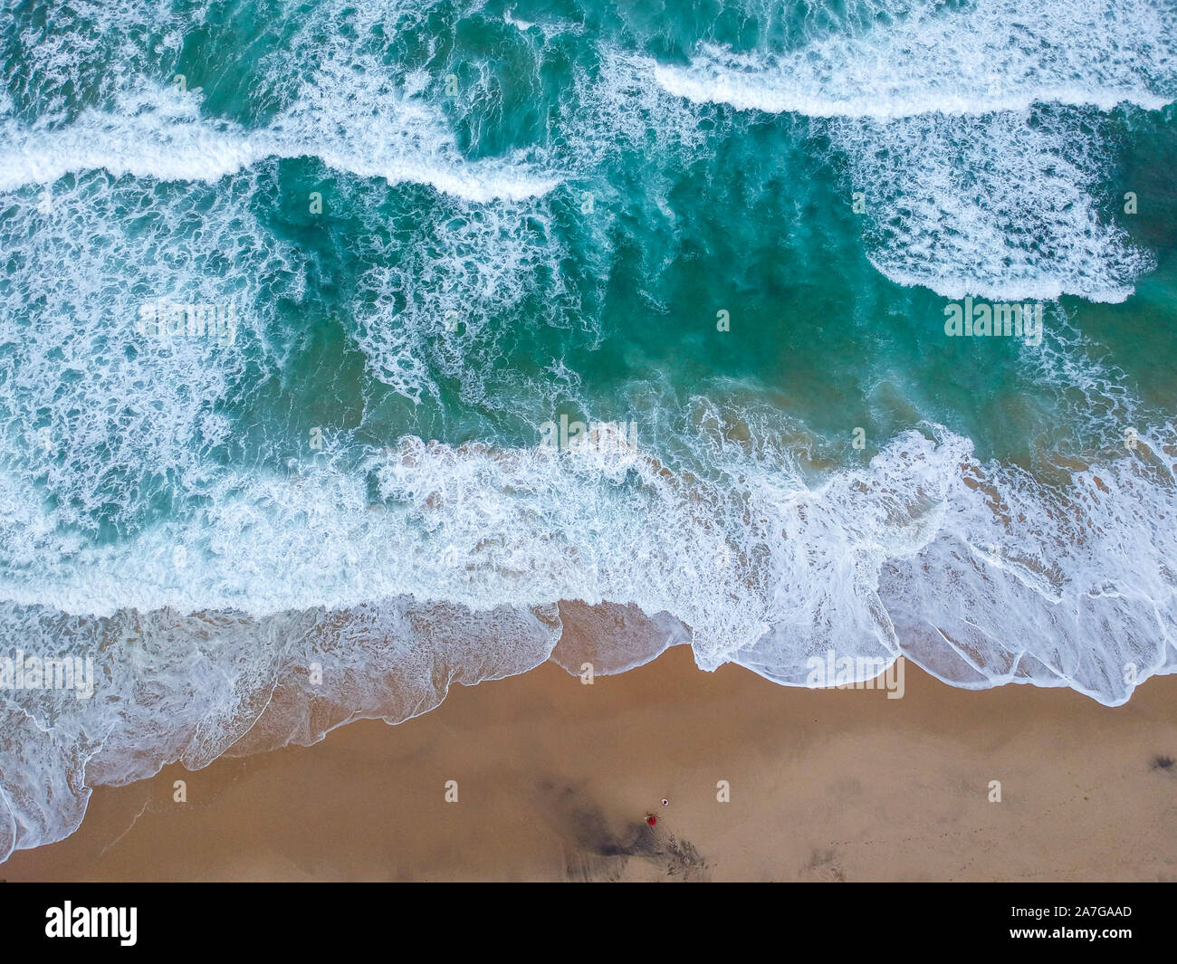 Sand beach aerial, top view of a beautiful sandy beach aerial shot with the blue waves rolling into the shore Stock Photo