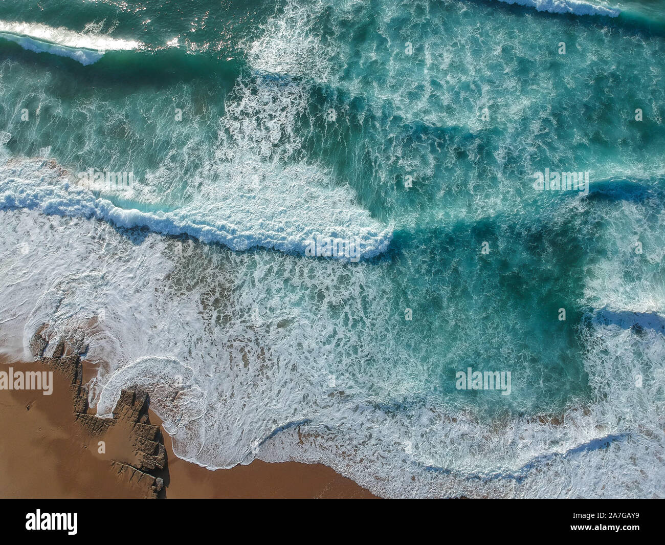 Sand beach aerial, top view of a beautiful sandy beach aerial shot with the blue waves rolling into the shore Stock Photo