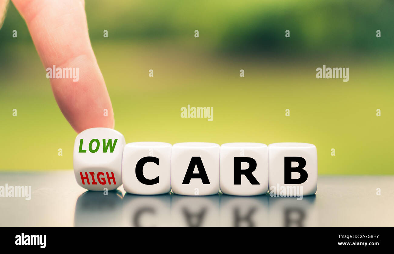Hand turns a dice and changes the expression from 'high carb' to 'low carb'. Stock Photo