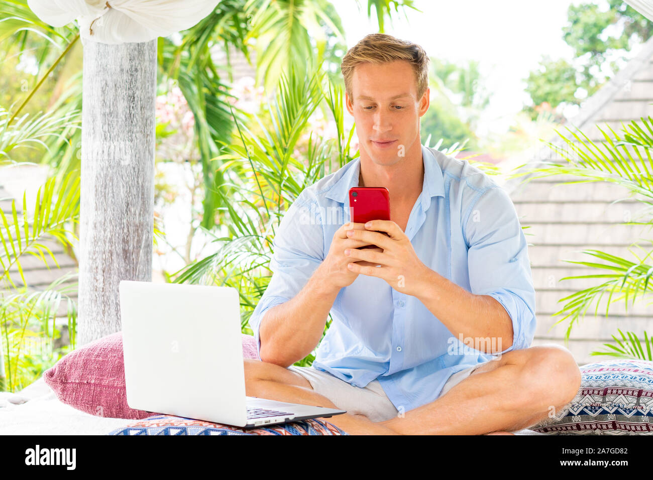 Attractive man using smartphone with palms on the background Stock Photo