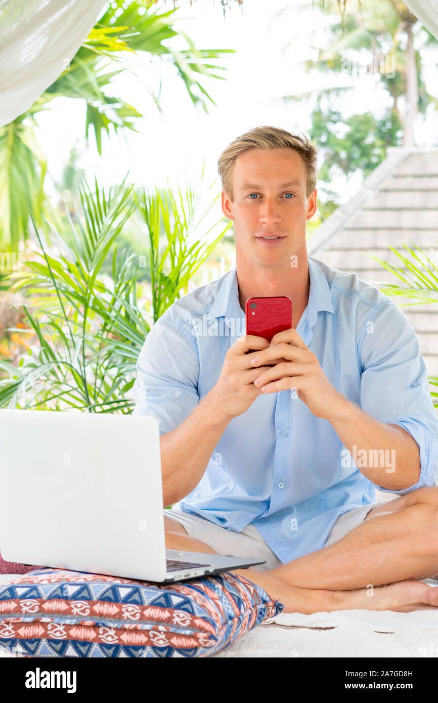 Attractive man using smartphone with palms on the background Stock Photo