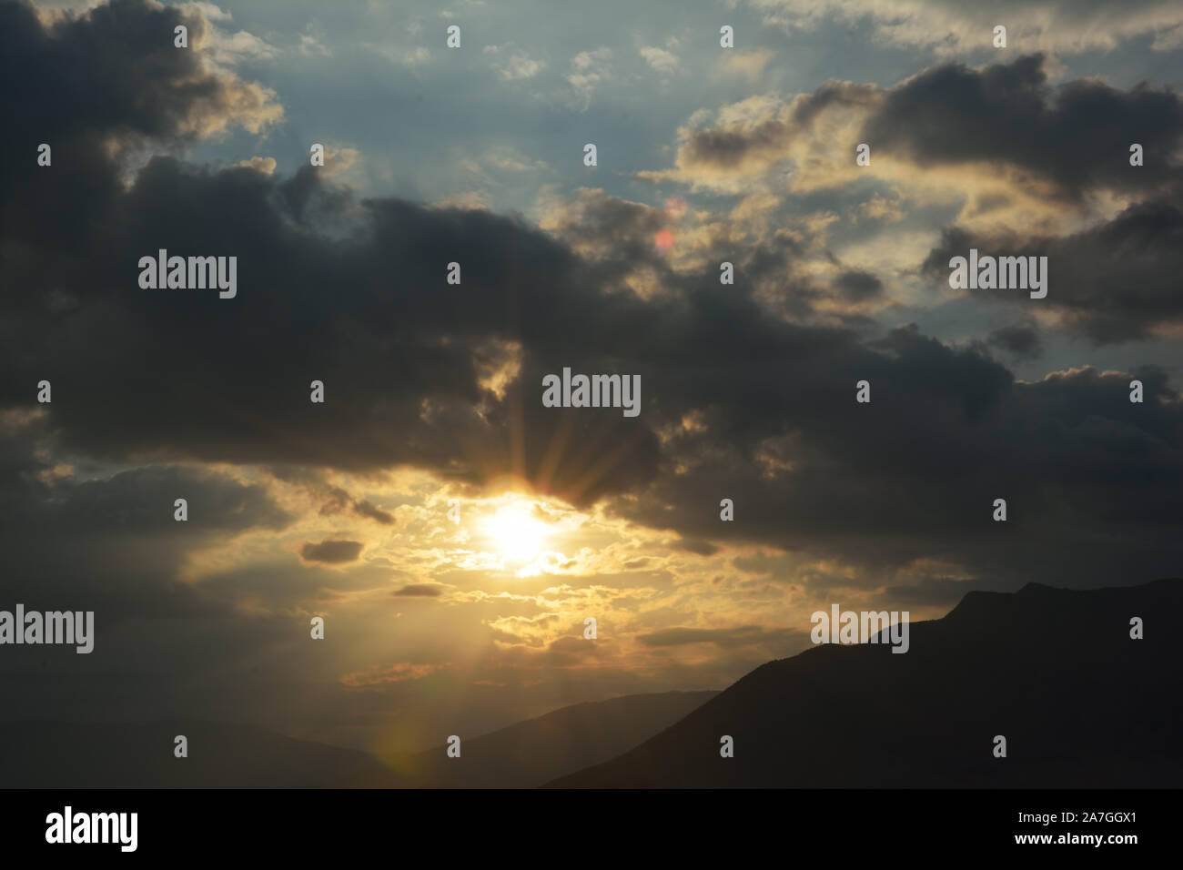 Sun shining through clouds over the mountain Stock Photo