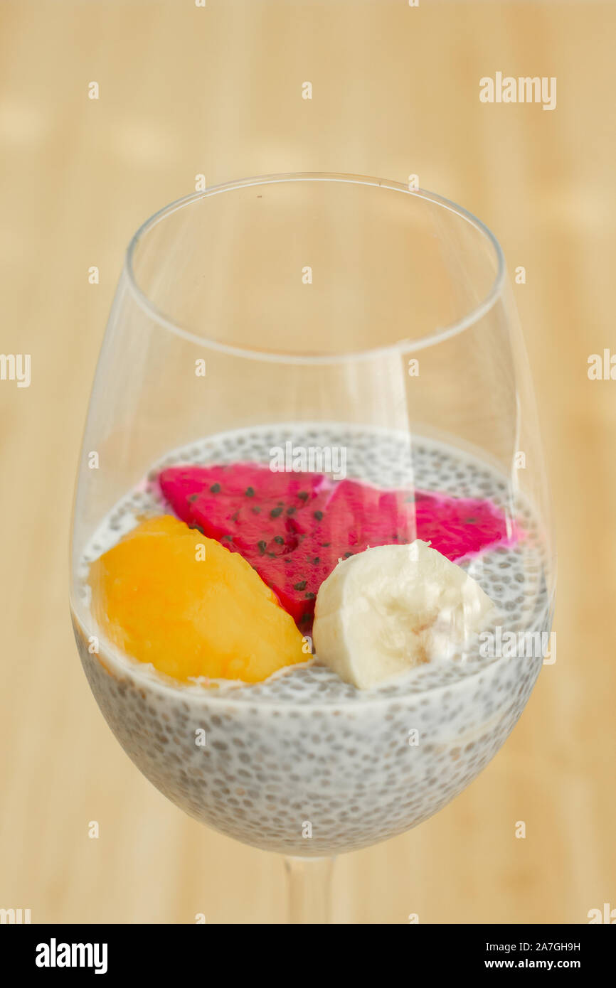 Glass of chia healthy food coconut pudding with banana, mango and dragon fruit on the bamboo background. Healthy concept Stock Photo