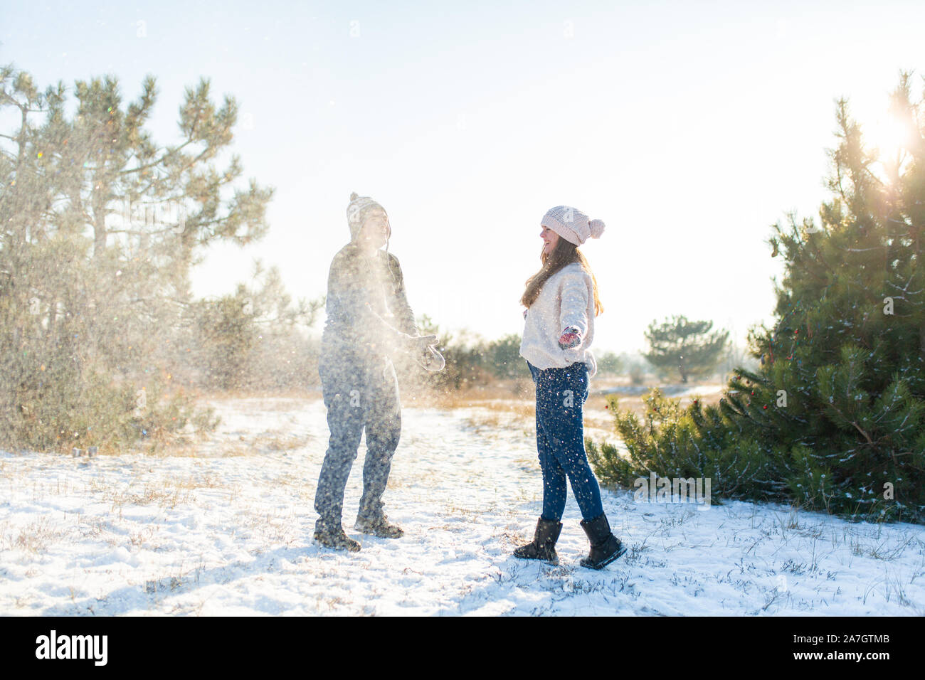 Loving couple play snowballs in winter in the forest. Throw each other ...