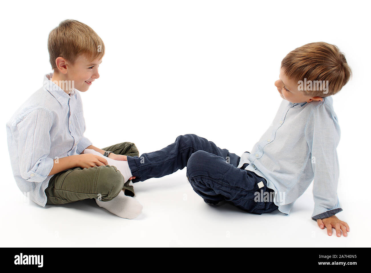 Cute boys are teasing each other by tickling their feet Stock Photo