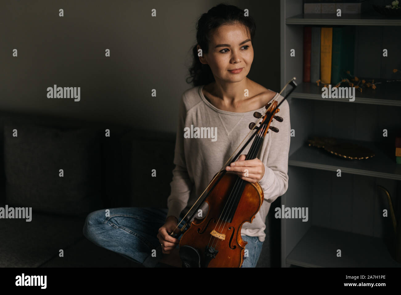Young woman posing with a violin at home Stock Photo - Alamy
